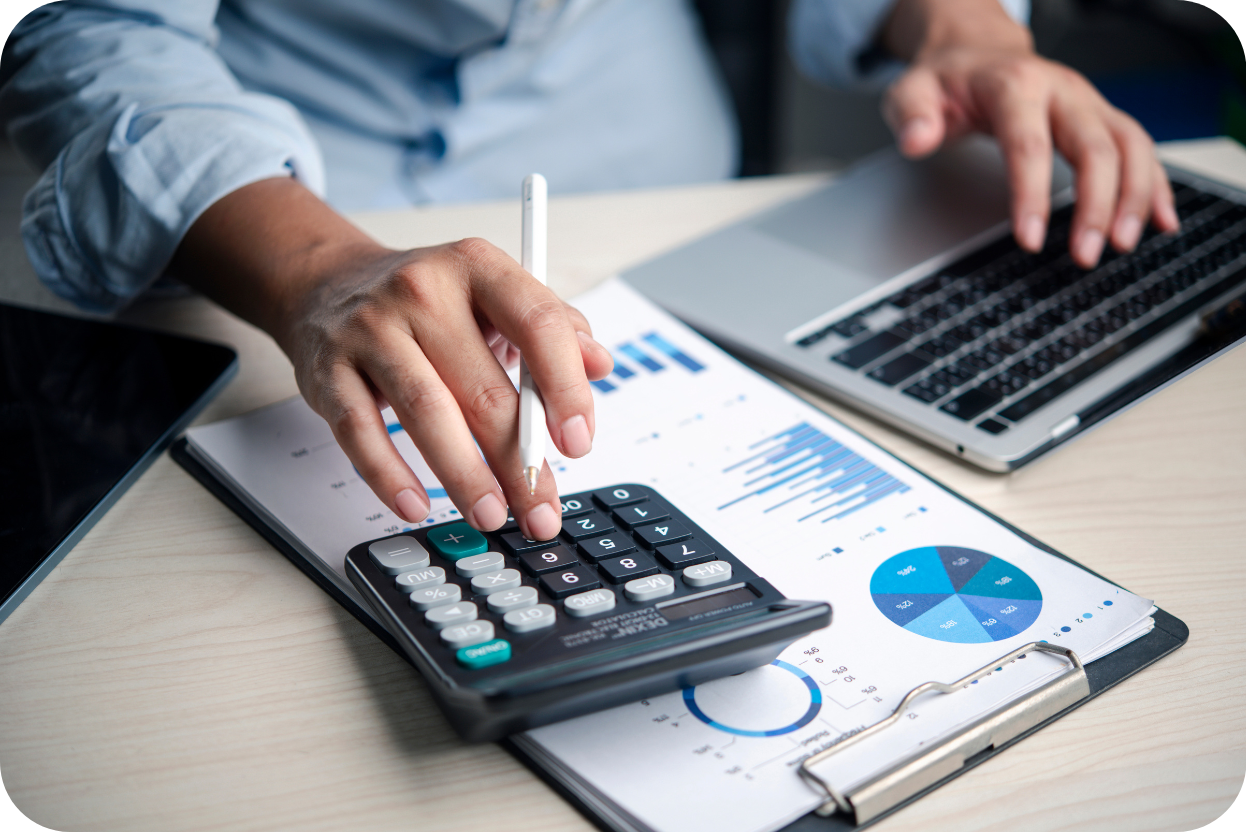 Mãos usando calculadora sobre relatórios e gráficos de previsão de custos de obra, simbolizando planejamento financeiro de projeto.